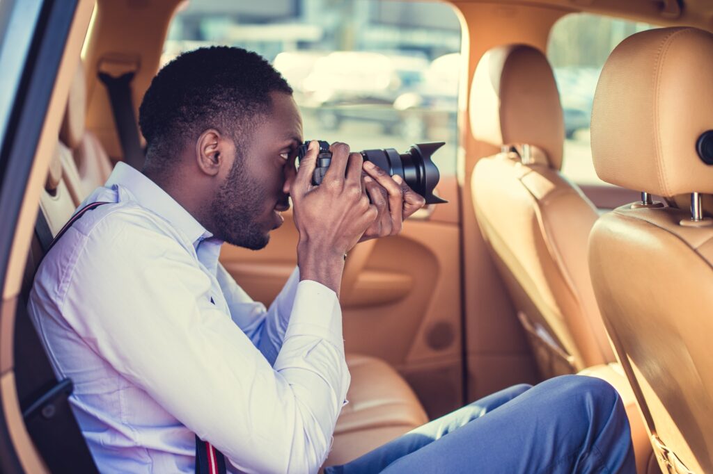 a black man using dslr camera in a car