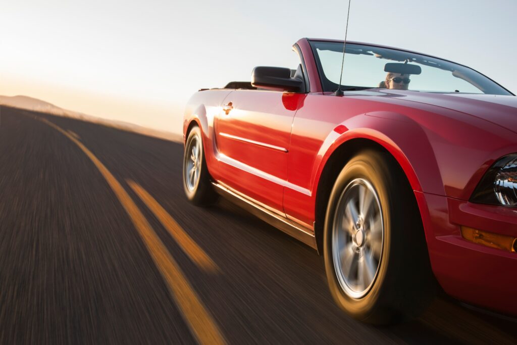a low angle view of a convertible sports car moving on a highway late in the day