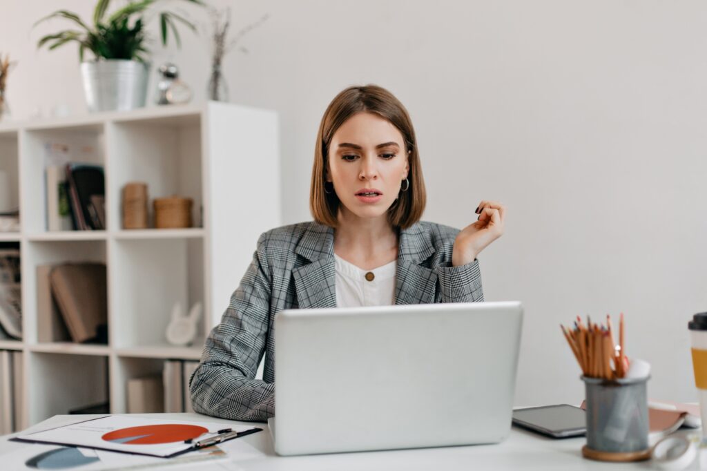 serious business woman with anxiety looks in macbook portrait of girl with short haircut in white