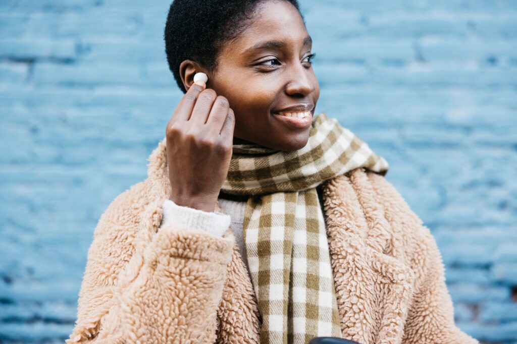 young woman wearing earbuds and smiling outdoors in winter